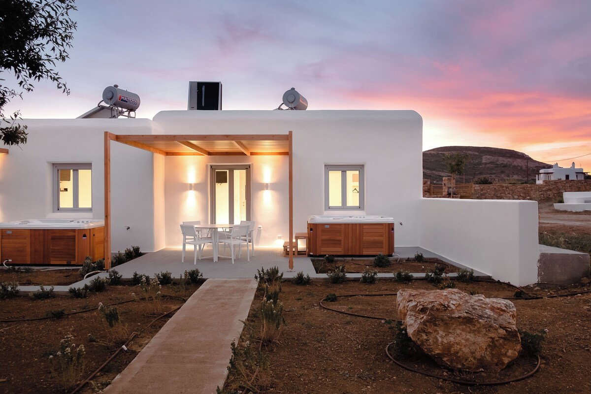 A modern white building with a patio, two wooden cabinets, and a large rock in the foreground.
