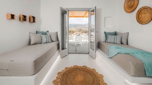 A modern room with two sofas, a woven rug, and a view through a glass door. - Xerolithos Natural Living (Naxos)