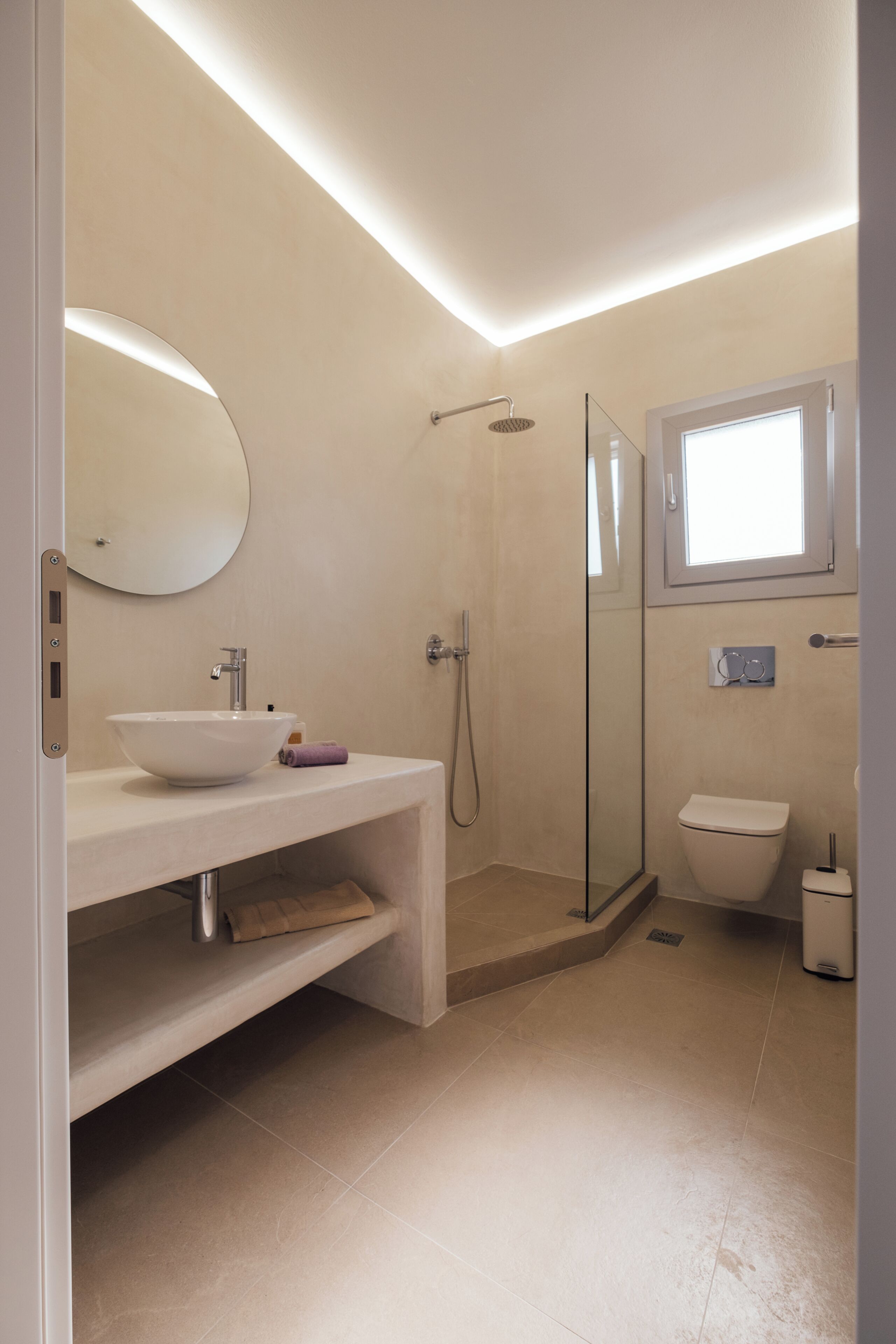 Une salle de bain moderne avec une douche à parois de verre, un lavabo avec un miroir et des toilettes.