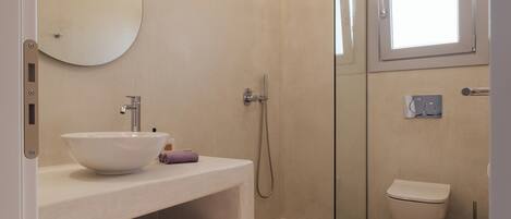 Une salle de bain moderne avec une douche à parois de verre, un lavabo avec un miroir et des toilettes.