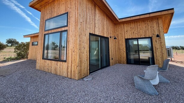 Et moderne træhus med store vinduer og en grusvej.