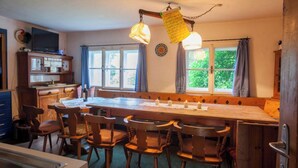 A cozy kitchen with a long wooden table, several chairs, and hanging lights. - Mountain-view Cottage 15 Beds-pets Welcome (Bramberg am Wildkogel)