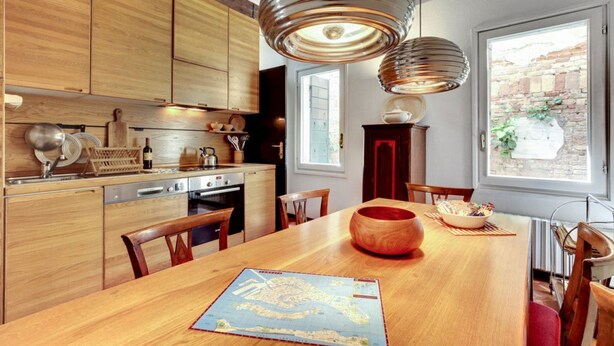 A modern kitchen with wooden cabinets, a dining table with a map, and pendant lights.