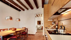 A modern kitchen with wooden cabinets, a dining area with a wooden table and chairs, and a visible kitchen island.