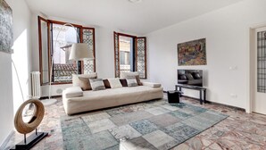 Ein Wohnzimmer mit einer Couch, einem Fernseher und einem gemusterten Teppich.
