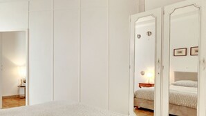 Ein Schlafzimmer mit einem Bett, einem Nachttisch, einem Spiegel und einer Tür.