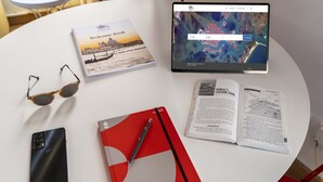 A table with a tablet displaying a map, a notebook, a pair of sunglasses, a smartphone, and a red folder. - CONTEMPORARY APARTMENT IN VENICE FF M02704212230 (Venice)