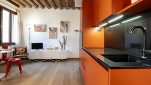 A modern kitchen with orange cabinetry, a black countertop, and a stainless steel sink. - CONTEMPORARY APARTMENT IN VENICE FF M02704212230 (Venice)