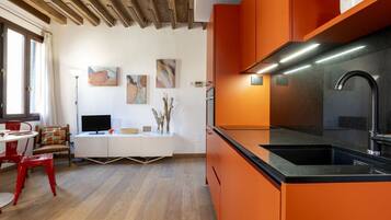 Una cucina moderna con mobili arancio, un piano di lavoro nero e un lavandino in acciaio inossidabile.