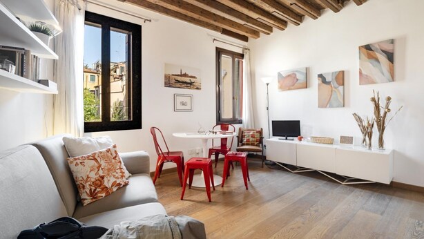 A modern living room with a sofa, red chairs, a dining table, and artwork on the walls. - CONTEMPORARY APARTMENT IN VENICE FF M02704212230 (Venice)