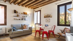 A cozy living room with a wooden ceiling, a grey sofa, red chairs, and a white table. - CONTEMPORARY APARTMENT IN VENICE FF M02704212230 (Venice)