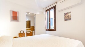 A bedroom with a large bed, a wooden door, a window, and a bathroom visible through an open door. - CONTEMPORARY APARTMENT IN VENICE FF M02704212230 (Venice)