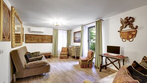 Ein geräumiges Wohnzimmer mit einer Couch, Sesseln, einem Fernseher und einem dekorativen Wandschild.