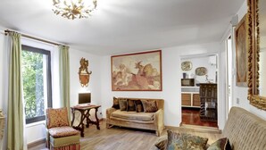 Ein geräumiges Wohnzimmer mit großem Fenster, einer Couch, einem Sessel und einem Gemälde an der Wand.
