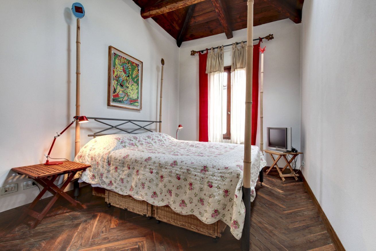 Une pièce comprenant un lit, un bureau, une chaise, un téléviseur et un tableau accroché au mur.