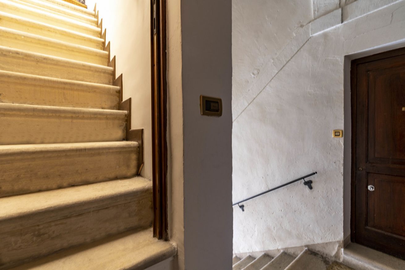 A staircase with a handrail, a door with a handle, and a small plaque on the wall.
