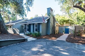 A residential house with a front yard, a driveway, and a wooden fence.