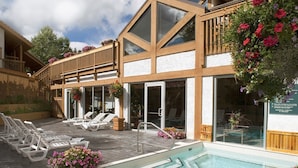 En moderne bygning med swimmingpool, liggestole og blomsterkasser.