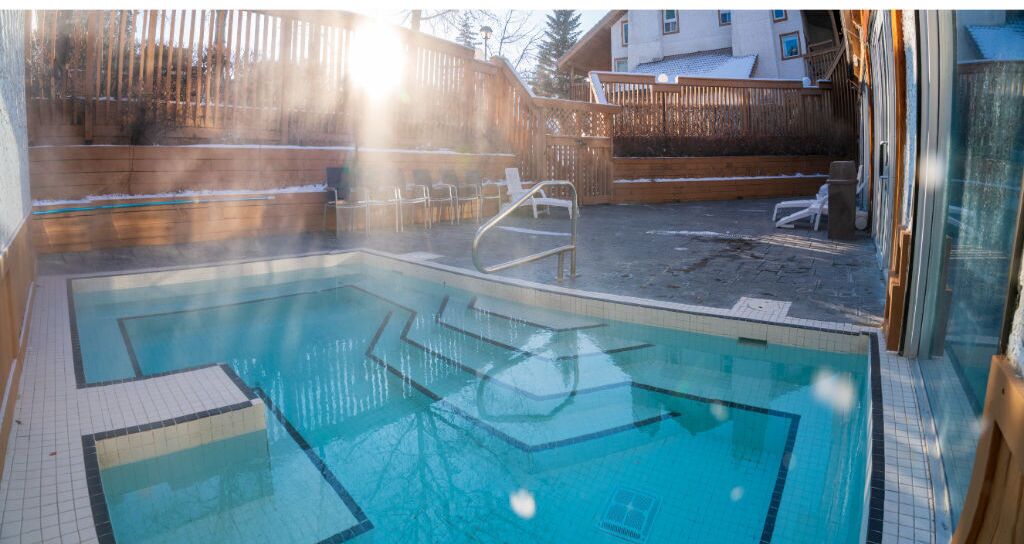 A swimming pool with a wooden deck and a wooden fence in the background.