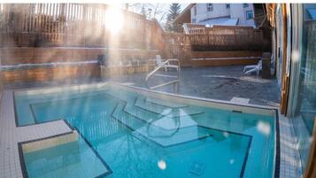 A swimming pool with a wooden deck and a wooden fence in the background.