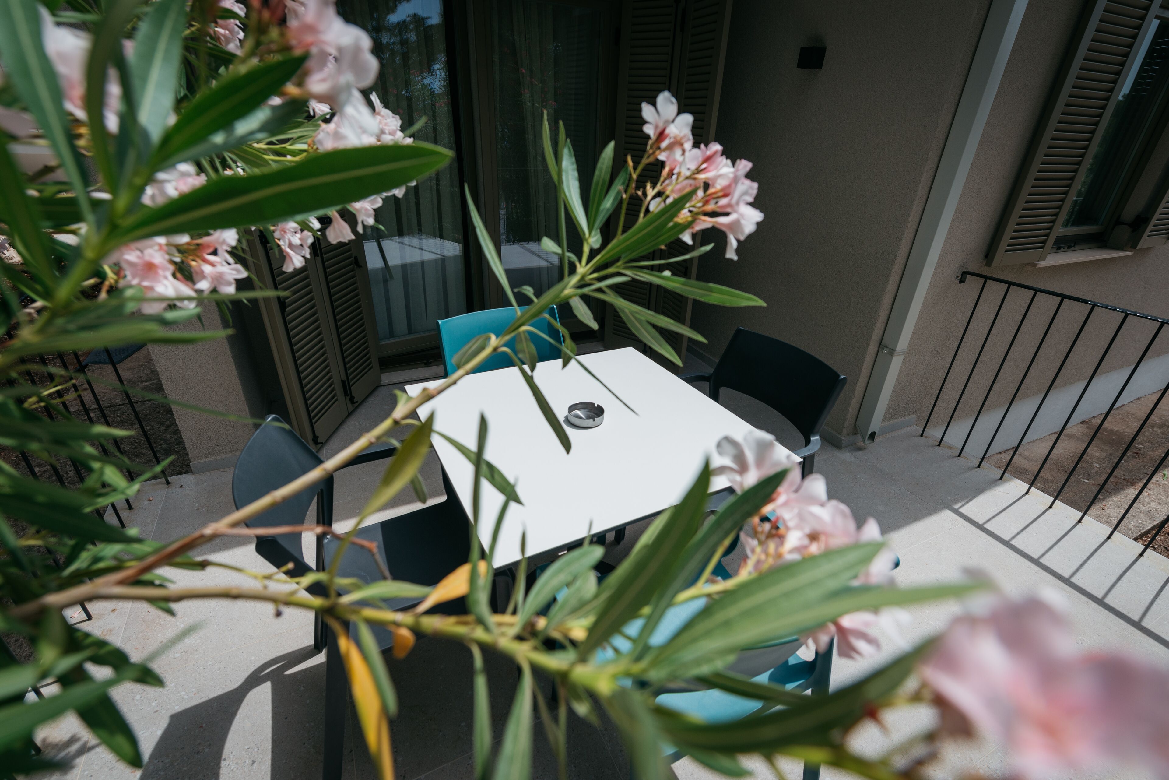 Een balkon met een tafel en stoelen, omringd door groen en bloemen.