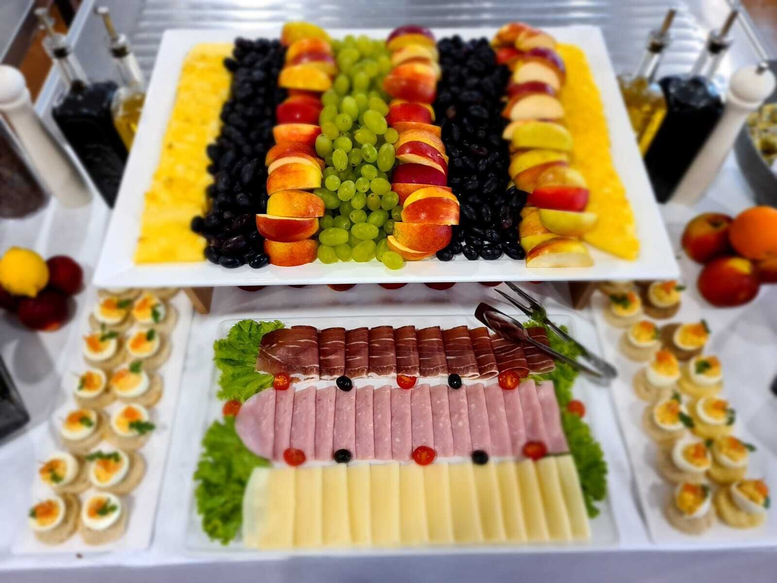 A buffet table with various food items including fruits, meats, and appetizers.