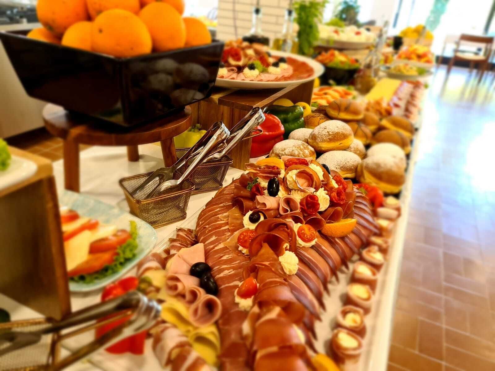 Ein Buffet mit verschiedenen Speisen, darunter Fleisch, Käse und Obst.