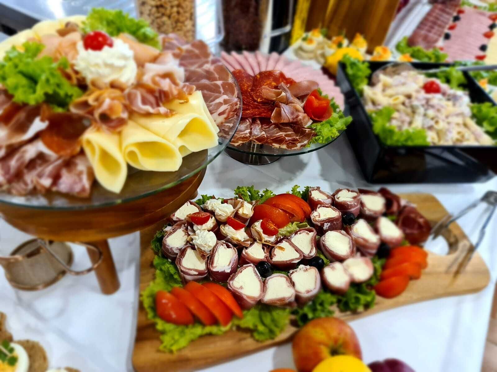 A buffet with various food items including pasta, meats, and cheese.