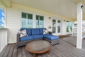 Eine überdachte Veranda mit einem blauen, modularen Sofa und einem runden Tisch.