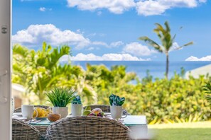 Enjoy a meal al fresco in this serene outdoor dining area surrounded by lush greenery and ocean views.