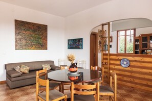 Un coin repas avec une table ronde, des chaises, un vase et un canapé.