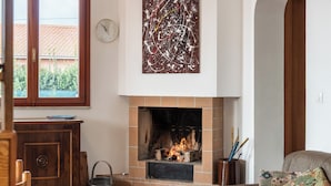 Una sala de estar con chimenea, un sofá, un aparador de madera y un reloj de pared.