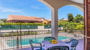 Un balcón con piscina, sillas y una mesa con limones.