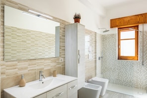 A bathroom with a large mirror, two sinks, a toilet, and a shower area.