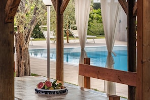 A wooden pergola with a pool in the background.