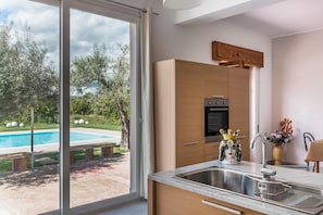 A modern kitchen with a large window, an oven, and a sink.