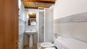 A compact bathroom with a pedestal sink, a shower, and a washing machine. - Iblea House - One Bedroom Apartment, Sleeps 4 (Avola)