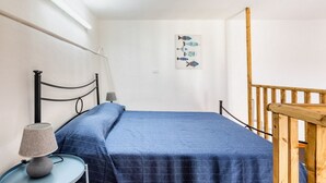 A bedroom with a bed, a nightstand with a lamp, a wooden railing, and a wall art piece. - Iblea House - One Bedroom Apartment, Sleeps 4 (Avola)