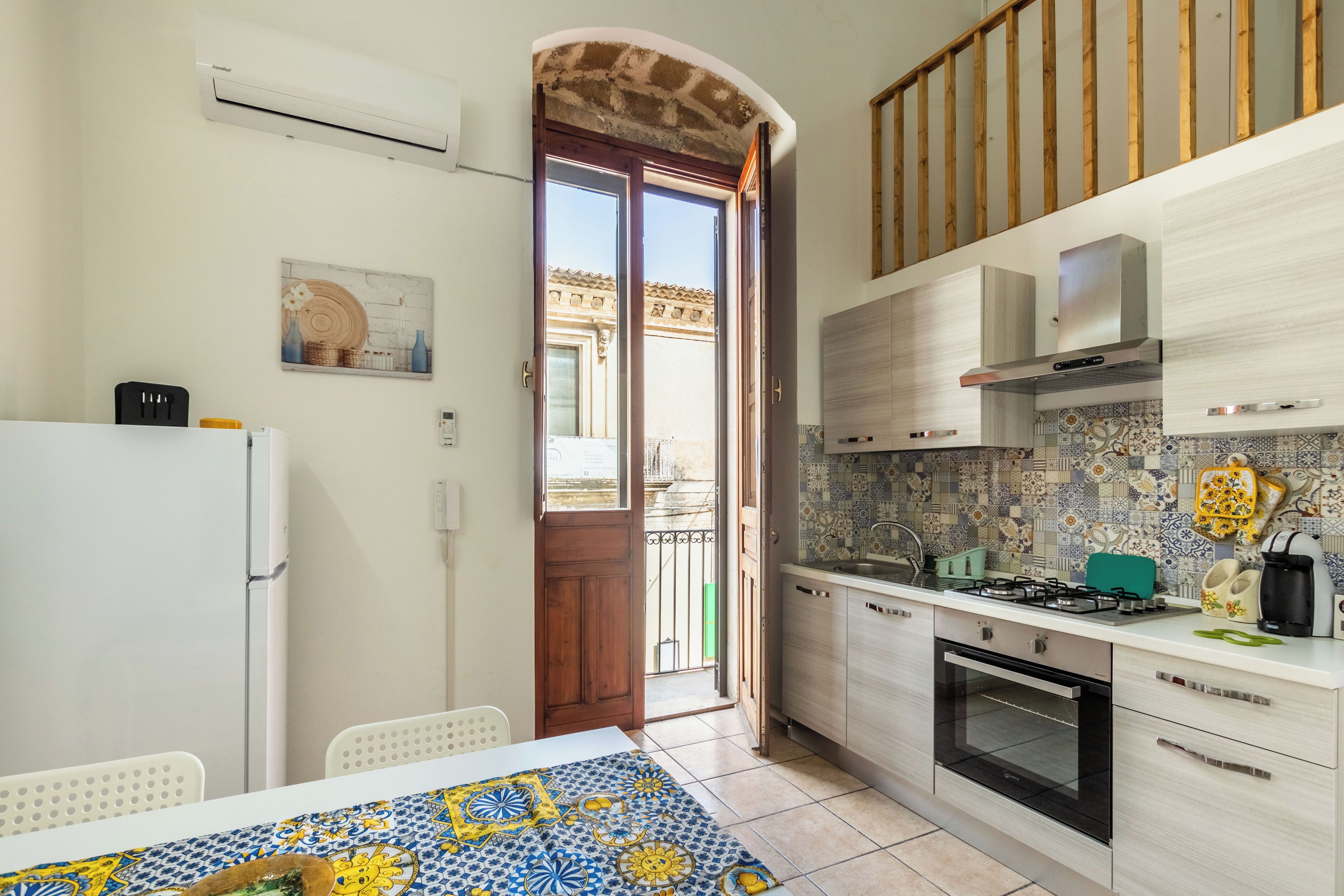 A compact kitchen with a dining area, featuring a tiled backsplash, a built-in oven, and a refrigerator.