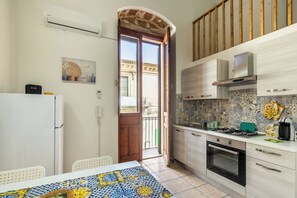 A compact kitchen with a dining area, featuring a tiled backsplash, a built-in oven, and a refrigerator.