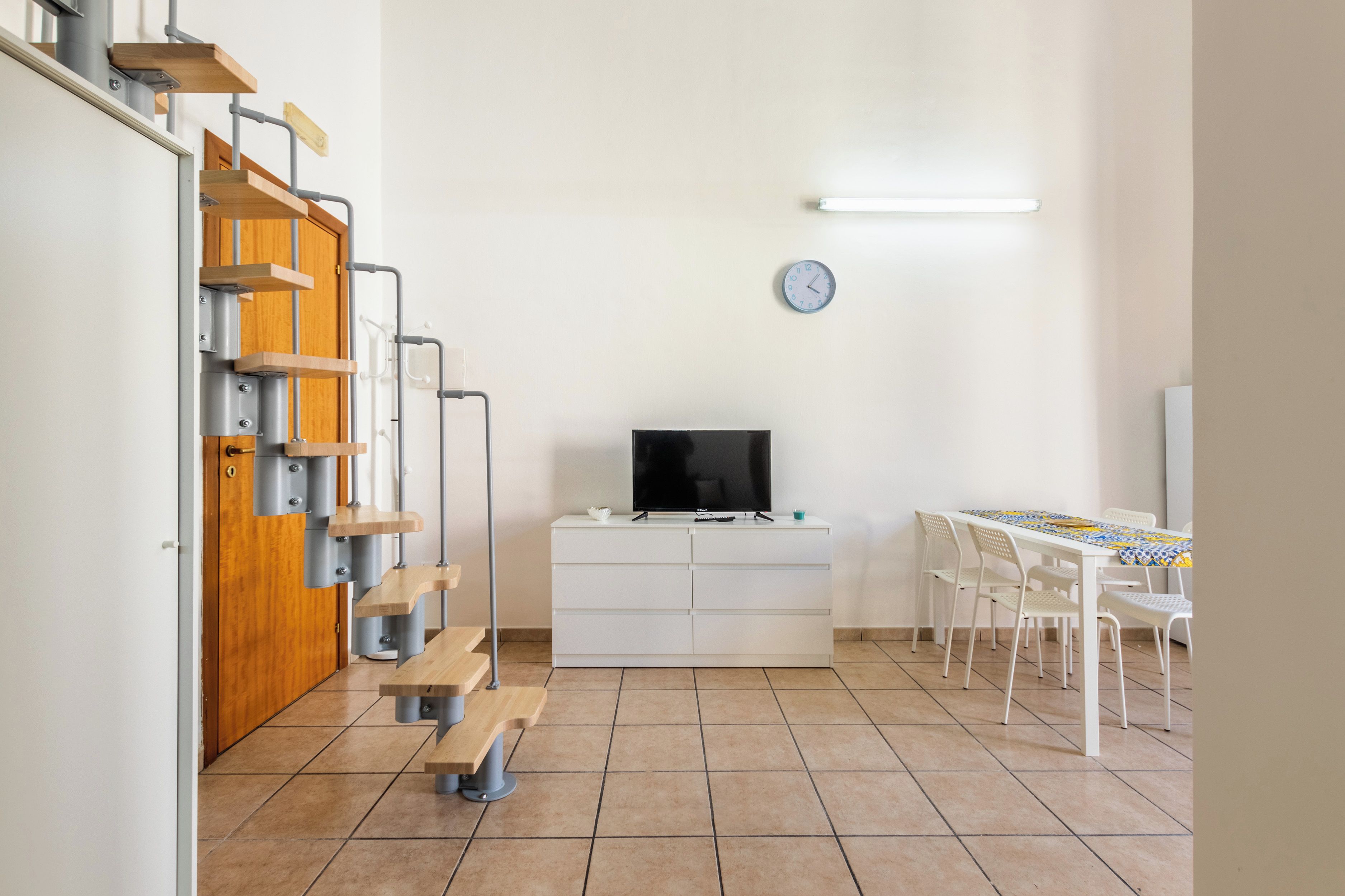 Una camera compatta con TV, tavolo e sedie.