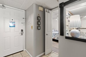 Un pasillo con puertas blancas, techo con textura y un equipo de aire acondicionado de pared.