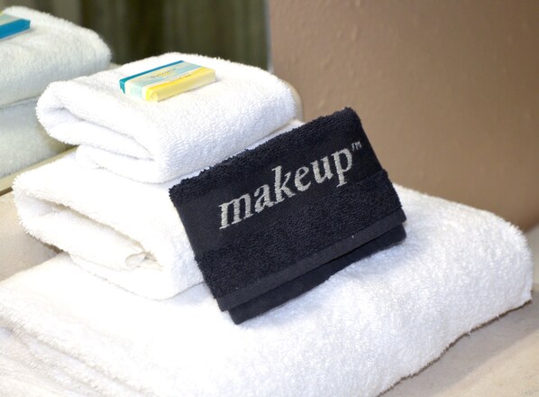 Une pile de serviettes blanches avec une étiquette noire sur laquelle est écrit « maquillage ».
