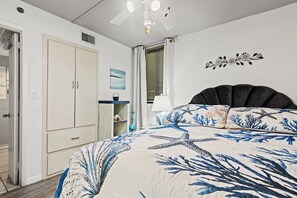 Une chambre à coucher comprenant un lit, une armoire, une fenêtre avec des stores et un ventilateur de plafond.