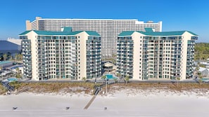 Ett högt hotell med flera balkonger, en swimmingpool och utsikt över stranden.