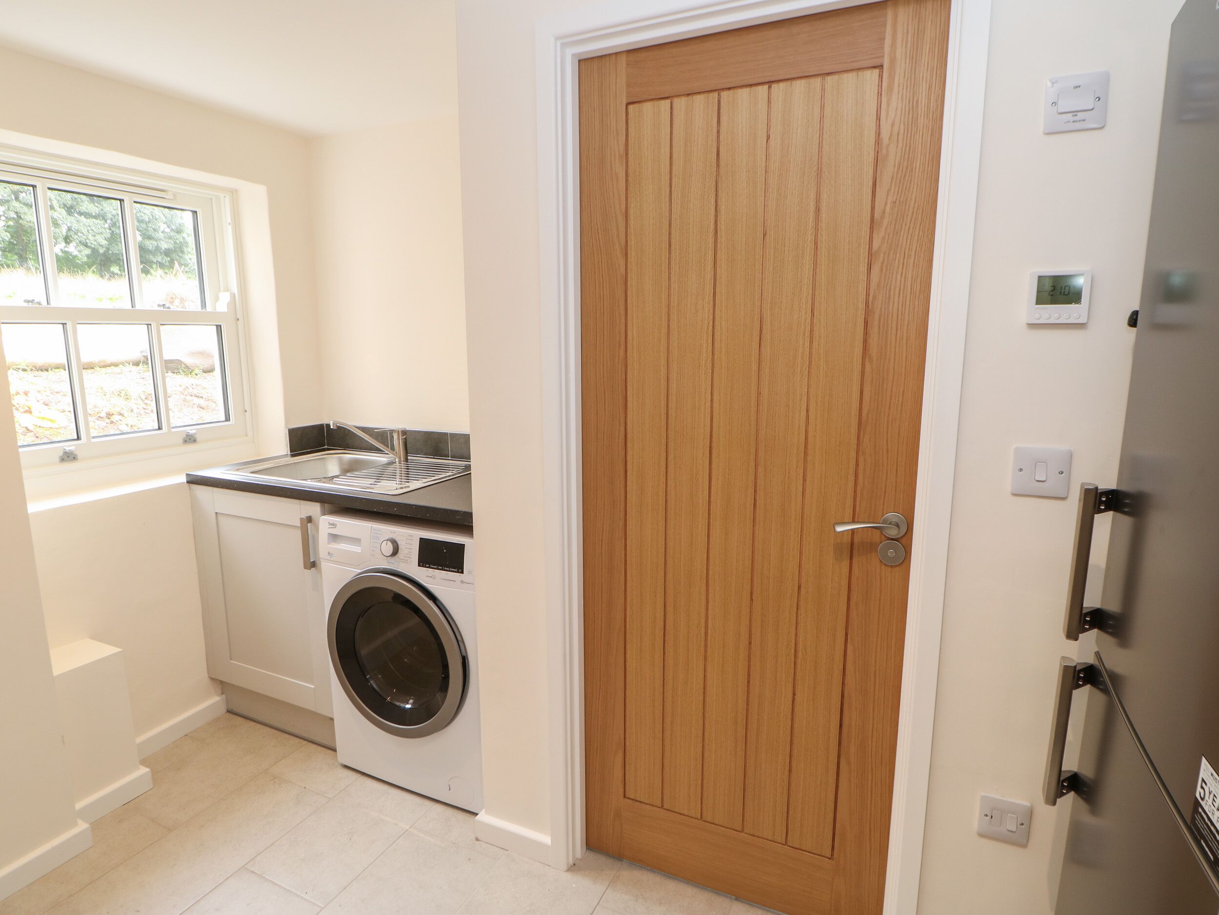 A compact laundry area with a washing machine, a drying rack, and a wooden door.