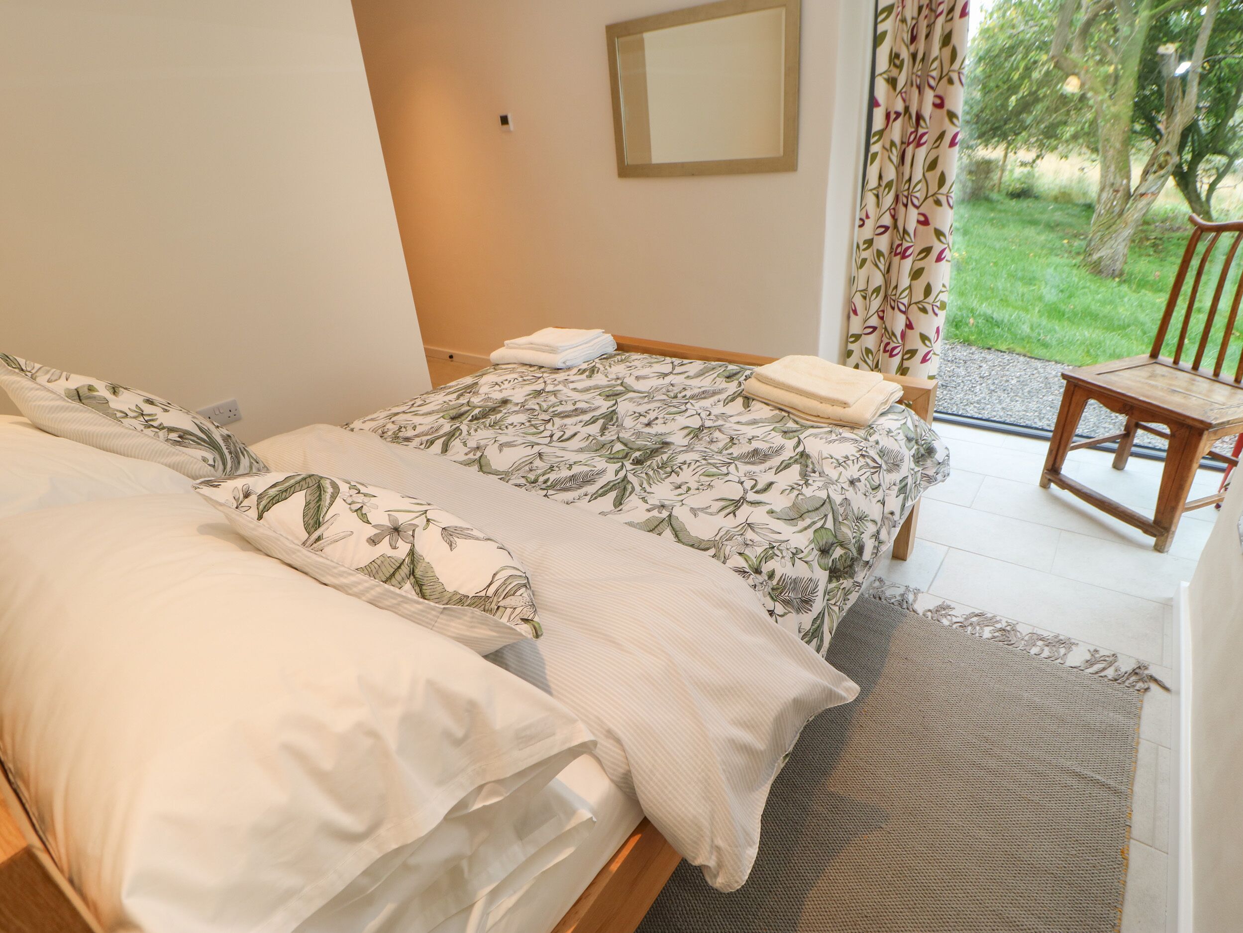 A bedroom with two beds, a small table, and a chair.