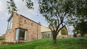 A stone building with large windows and a tree in front.