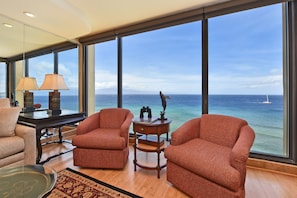 Enjoy ocean views from the large window in this room, which features two armchairs, a side table, and a coffee table.