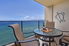 Enjoy ocean views from this balcony with a round table, two comfortable chairs, and a decorative sculpture.